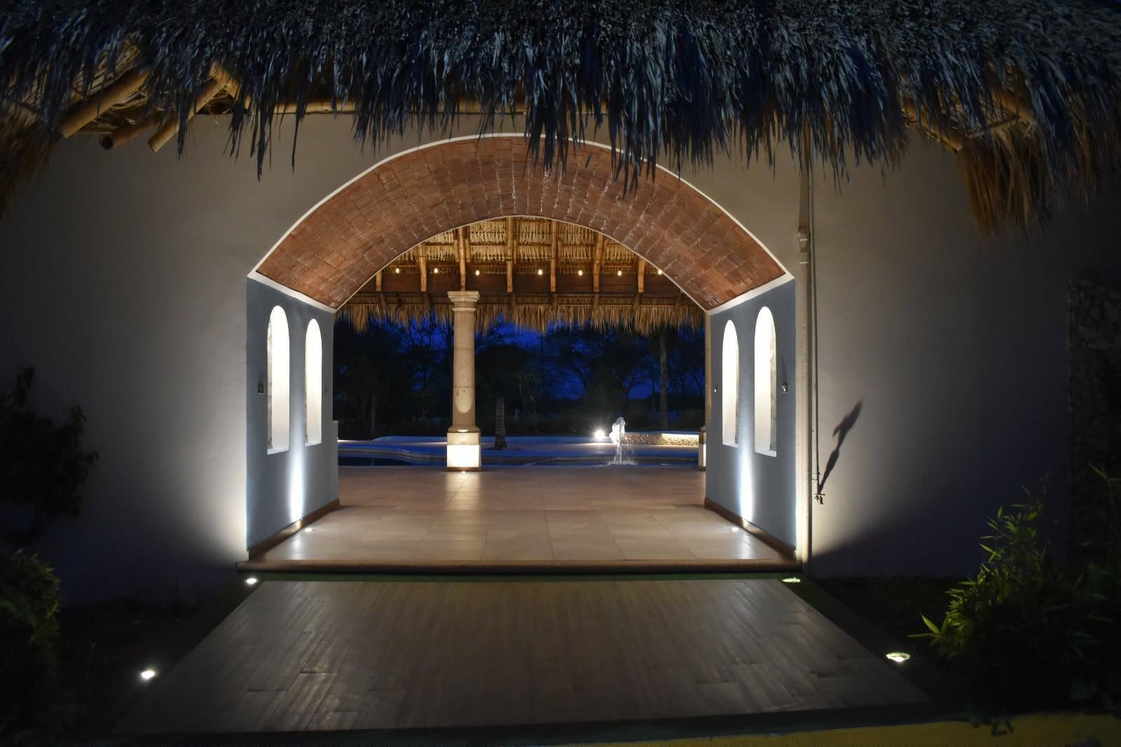 Entrada en arco hacia la alberca y la palapa de noche