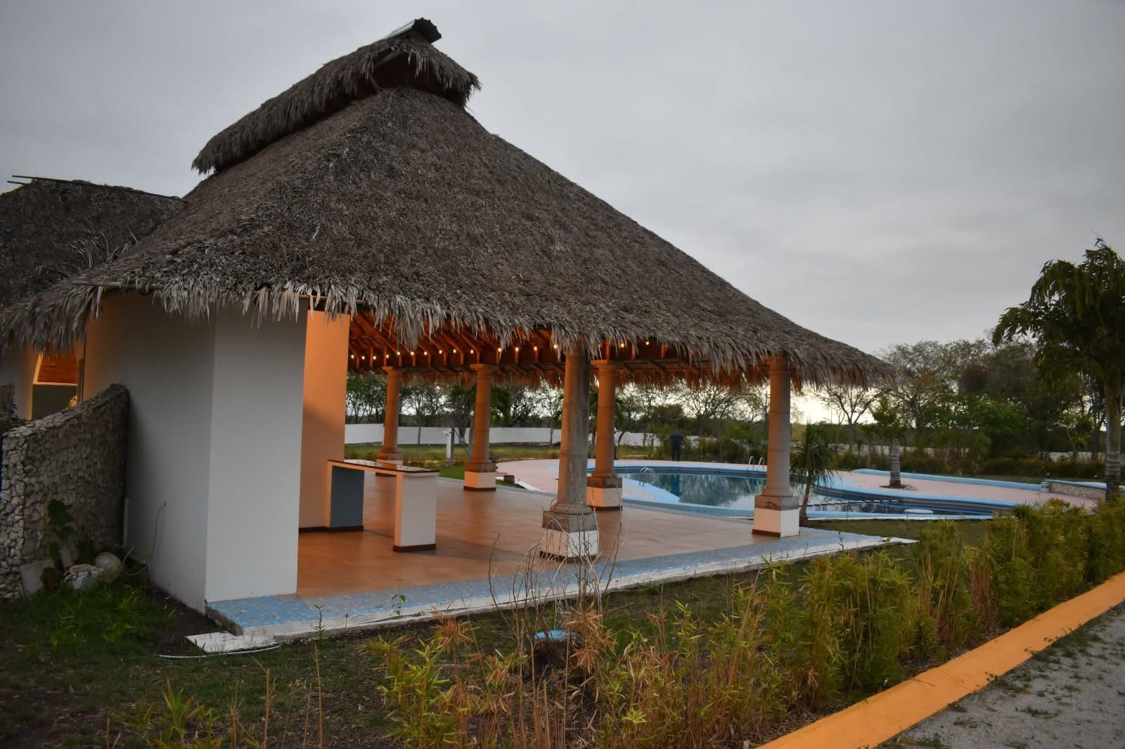 Vista de la palapa y la alberca completa al atardecer
